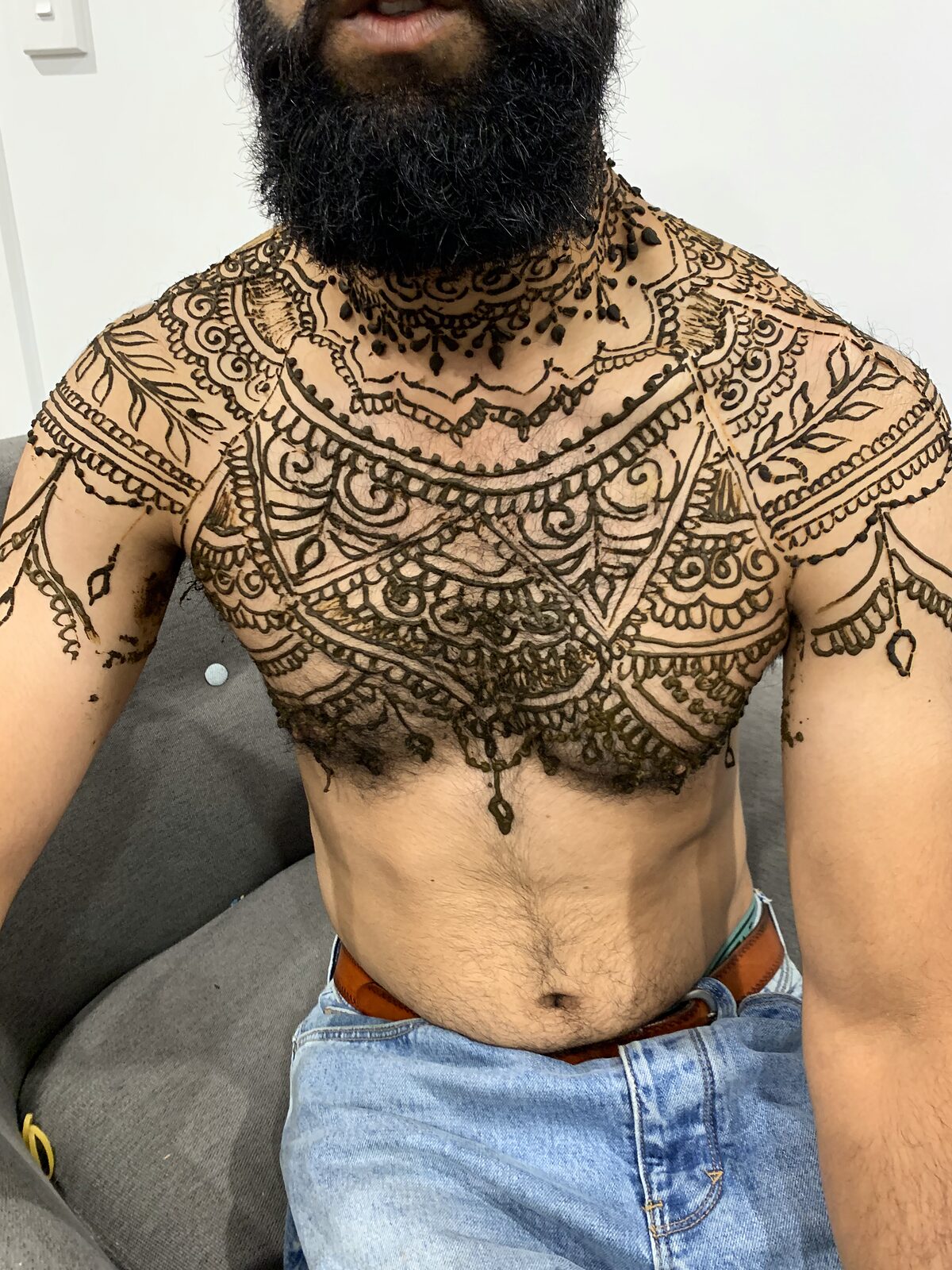 Freehand henna across a man's chest and shoulders