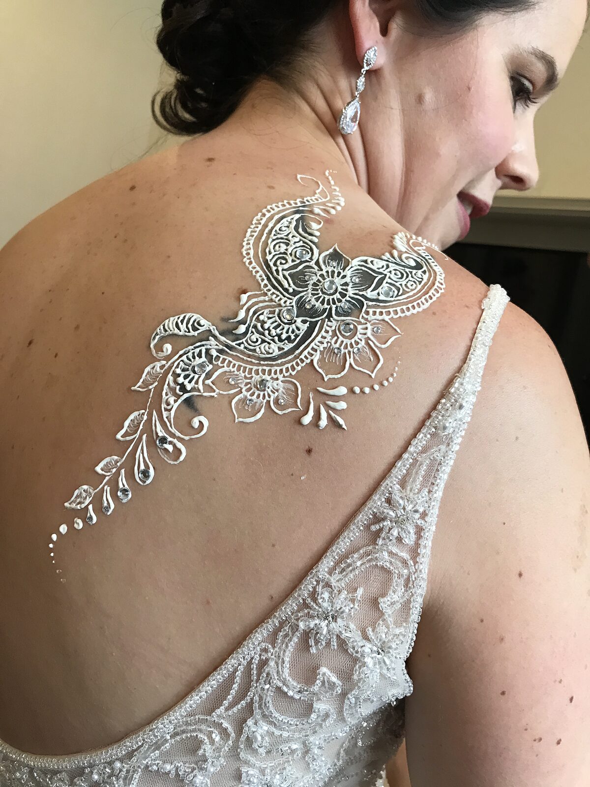 White henna on a bride's shoulder, in her wedding dress