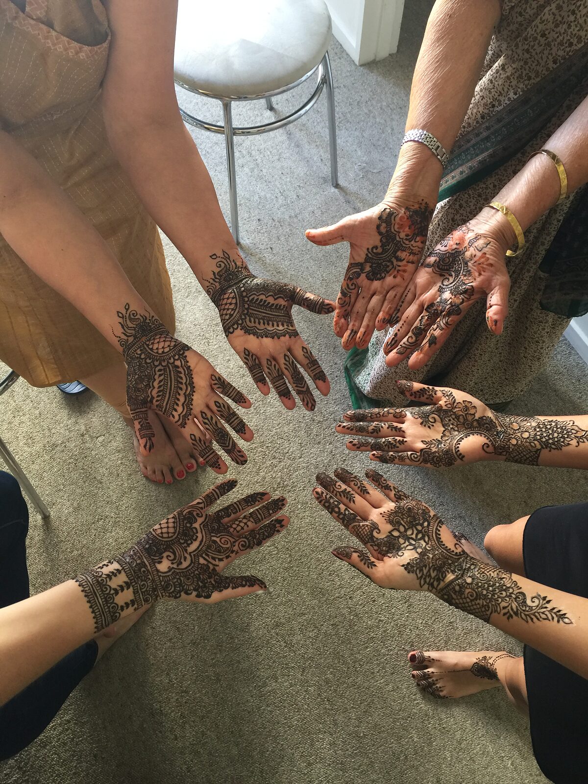 A circle of hennaed hands at a party
